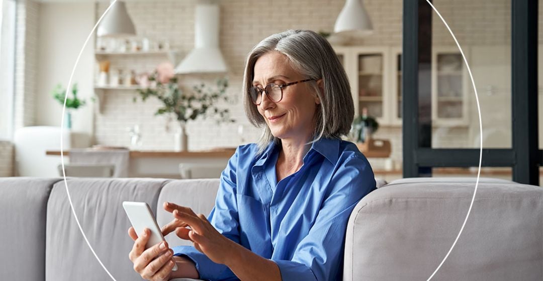 Photo of a woman sitting on a couch smiling at her phone